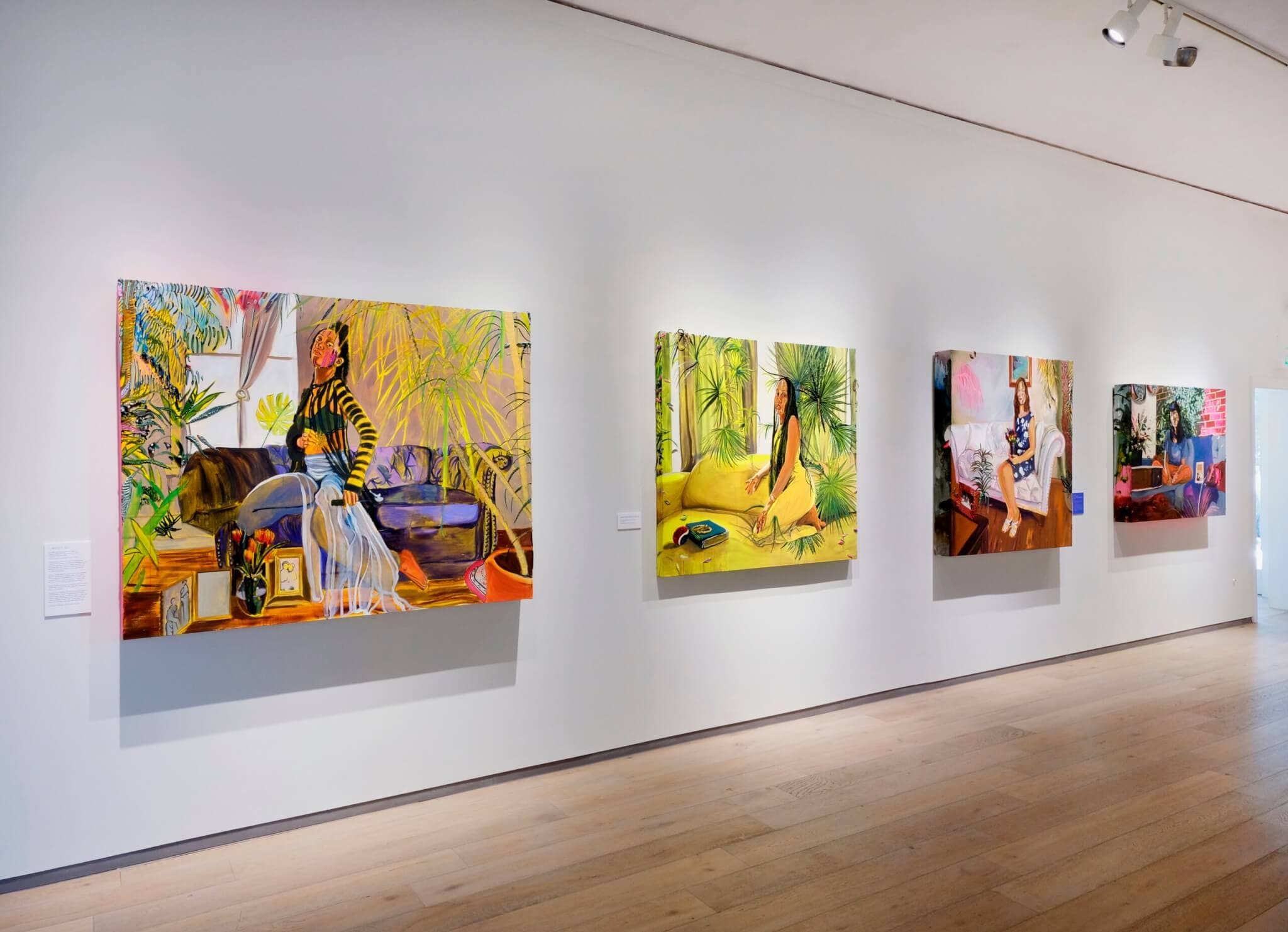 Vibrant portraits of Indigenous women hang on the white walls of a gallery.